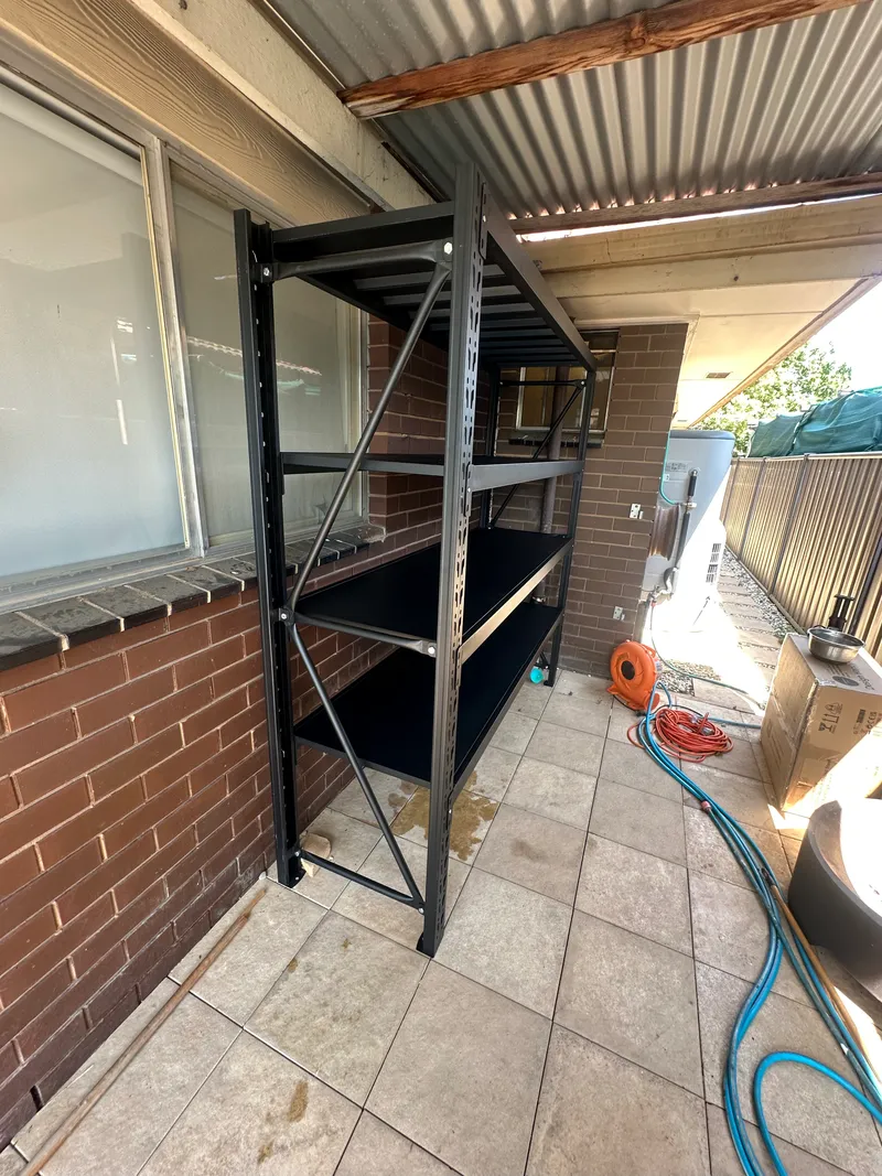 Black metal shelves against brown brick wall