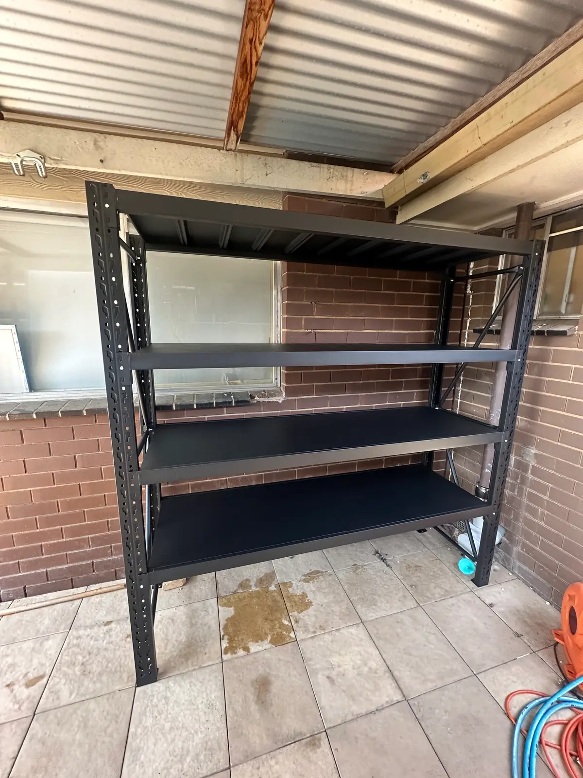 Black metal shelves in outdoor brick area