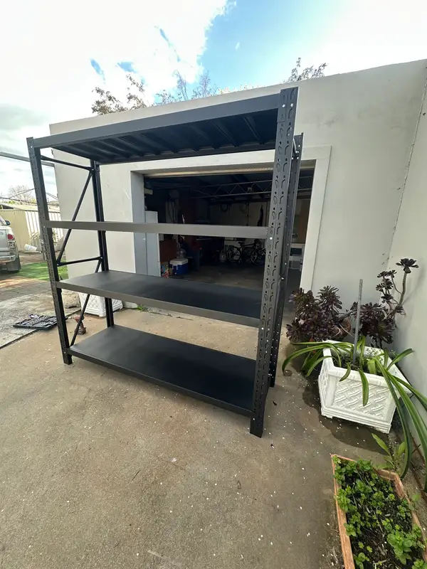 Black metal shelving outside white garage building
