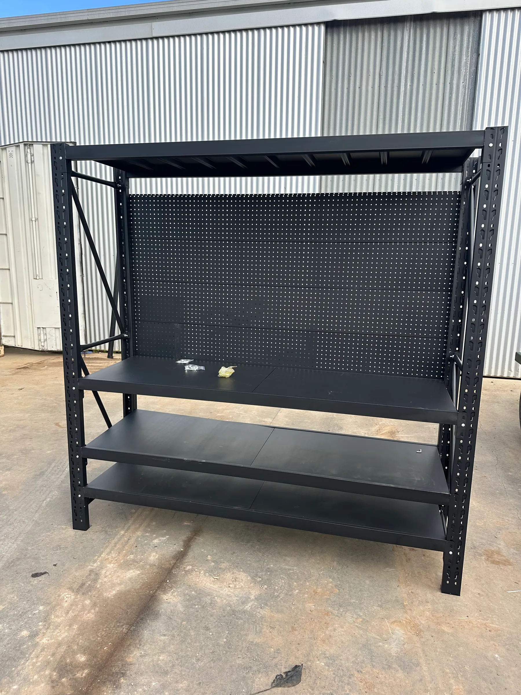 Black metal shelving unit with pegboard backing