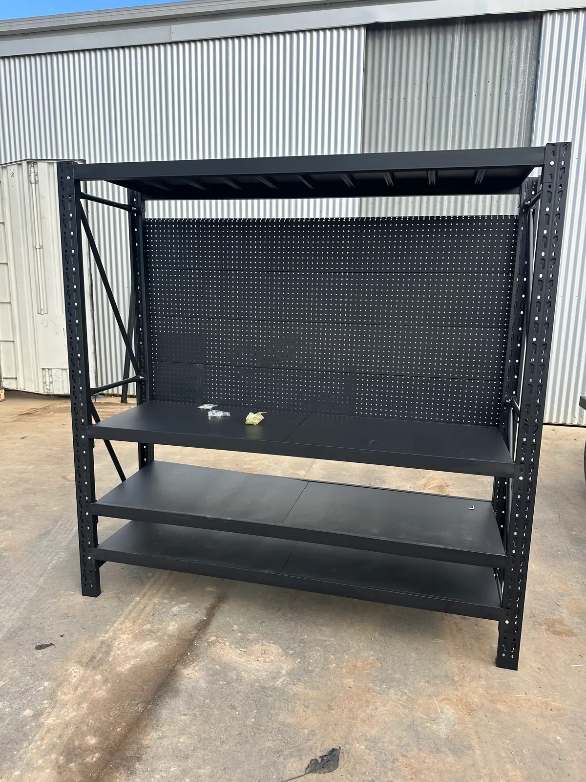 Black metal shelving unit with pegboard backing