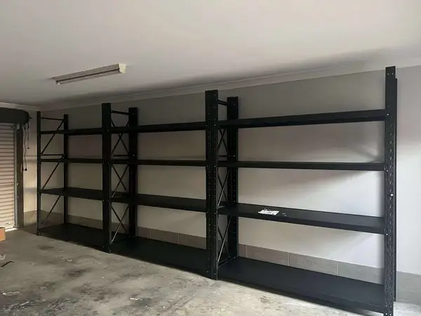 Empty black metal shelves against gray wall