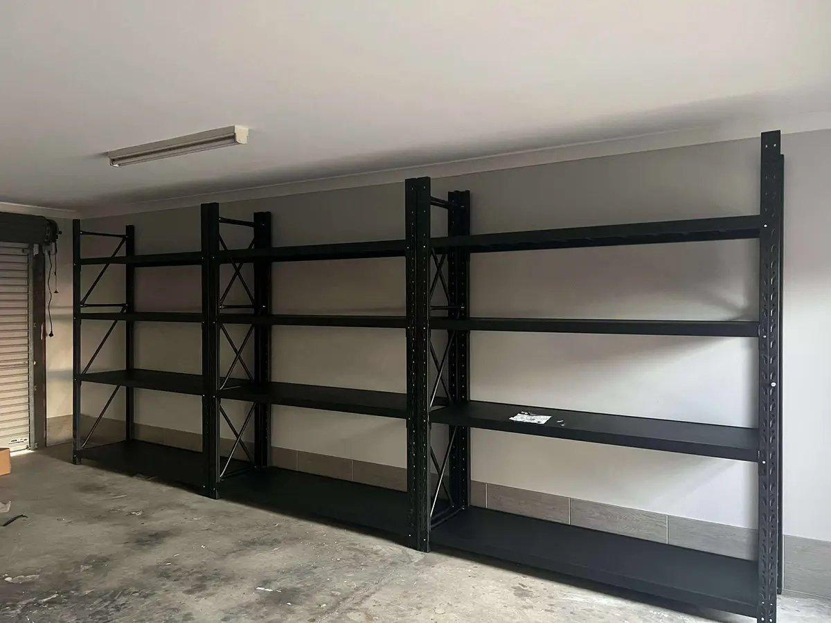 Empty black metal shelves against gray wall