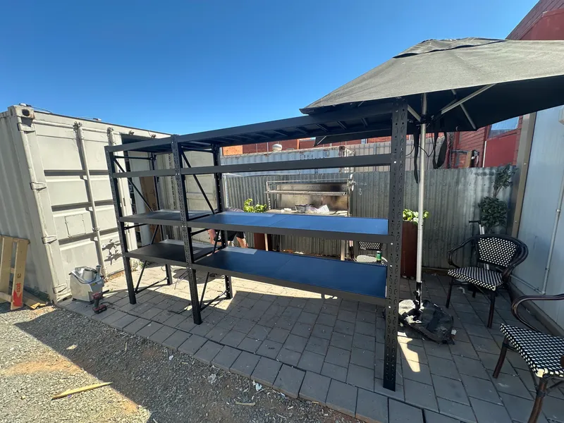 Metal shelves and patio chairs under umbrella